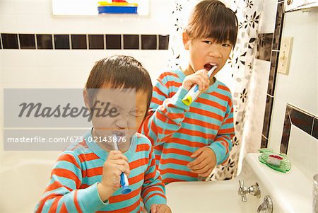 Asian siblings brushing teeth