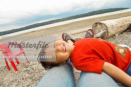 Asian boy se trouvant sur les jambes de la mère