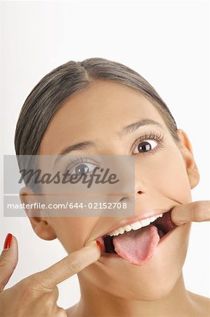 Weibliche junge Erwachsene Gesicht; Dehnung Mund öffnen, Zunge heraus