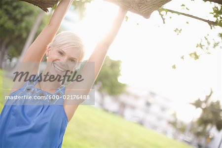 Portrait of Woman Hanging from Tree Branch