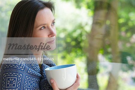 Woman with a cup, looking outside