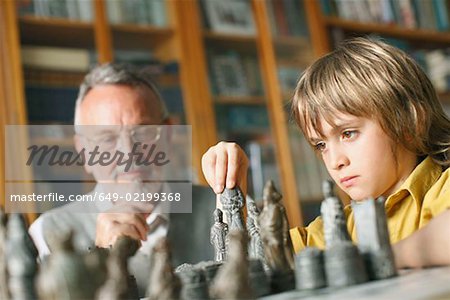 Kleiner Junge spielt Schach mit Großvater