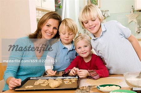 Mutter und drei Kinder backen Kekse