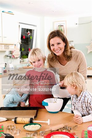 Mother and three children in kitchen baking biscuits