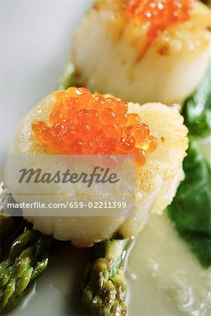 Coquilles Saint-Jacques avec caviar de saumon sur les asperges