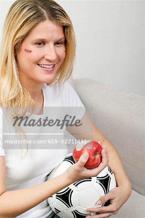 Young women with football eating an apple