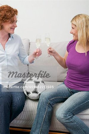 Two friends with sparkling wine and football