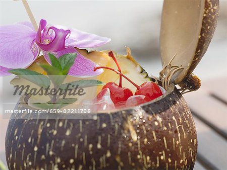 Coconut drink with pineapple, cocktail cherry and orchid