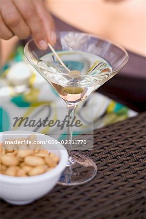 Femme tenant vert olive sur cocktail bâton en verre à Martini