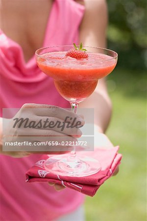 Woman holding fruity strawberry drink out of doors Woman holding fruity strawberry drink out of doors