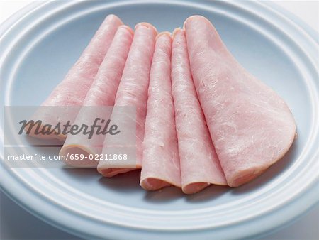 Several slices of ham on light blue plate