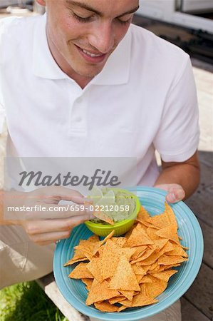 Junger Mann Essen Tortilla Chips mit guacamole