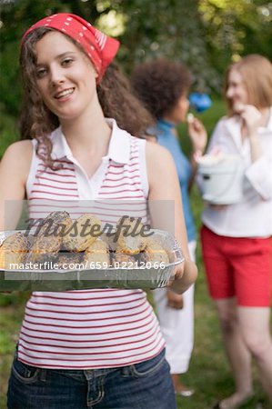 Young woman serving grilled corn on the cob at a barbecue