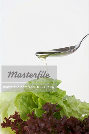 Pouring oil onto mixed salad leaves