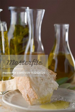 Pain blanc avec l'huile d'olive, bouteilles d'huile en arrière-plan