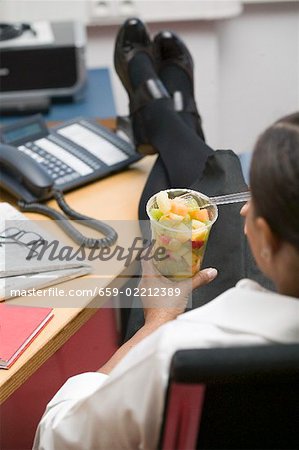 Femme, manger de la salade de fruits au bureau