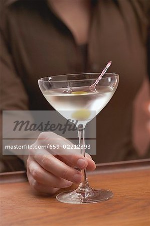 Woman holding glass of Martini with olive