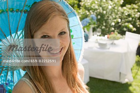 Woman with parasol in front of table laid out of doors