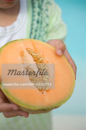 Enfant tenant la moitié un melon cantaloup