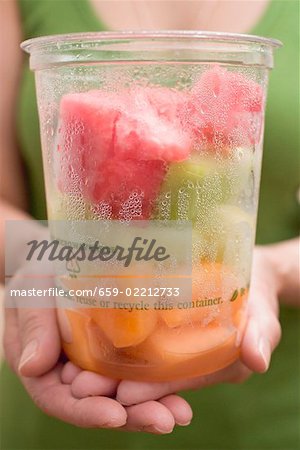 Woman holding plastic tub of diced melon