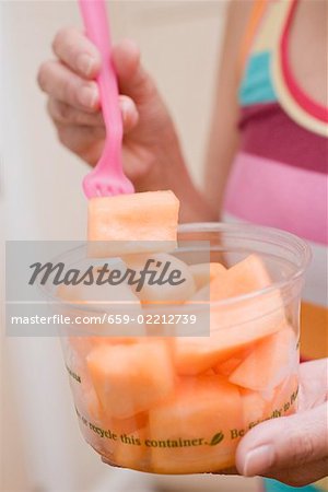 Femme mangeant melon en dés hors cuve en plastique