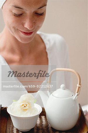 Frau hält Tablett mit Tee und weißen Blüten