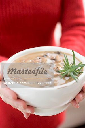 Woman holding bowl of mushroom sauce with rosemary