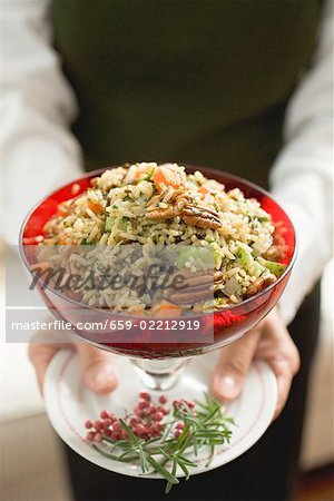 Femme tenant le bol de riz légume aux noix de pécan (Noël)