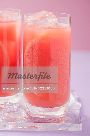 Deux verres de jus de pamplemousse rose avec des cubes de glace