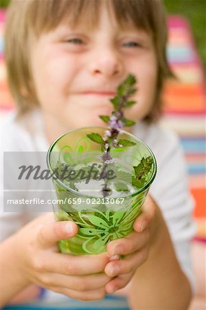 Small boy holding glass of cold peppermint tea