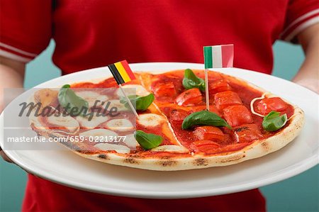 Female footballer holding tomato & mozzarella pizza with flags