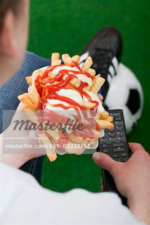 Football fan holding chips and remote