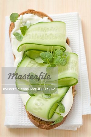 Yoghurt, cucumber slices and herbs on slice of bread