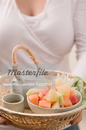 Femme tenant un thé et salades de fruits en panier