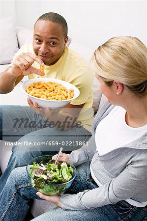 Paar auf Sofa mit Erdnuss Puffs und Salat