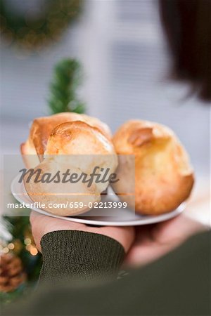 Hands holding plate of popovers (Christmas)