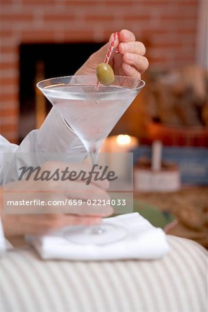Mains tenant le verre de Martini avec olive