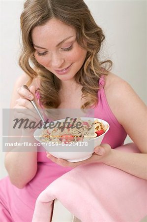Woman eating cornflakes with strawberries