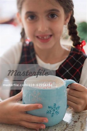 Girl holding large mug of cocoa with pieces of candy cane