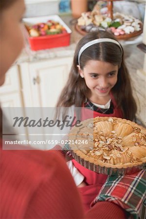 Woman holding apple tart, girl in background