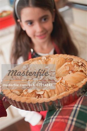 Hands holding apple tart, girl in background