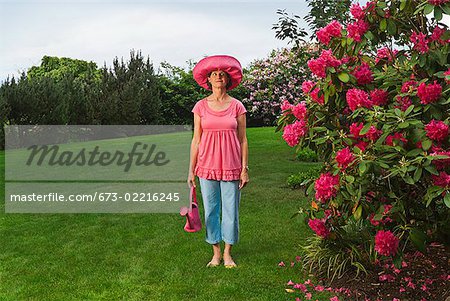 Femme en due forme chapeau rose festive dans le jardin
