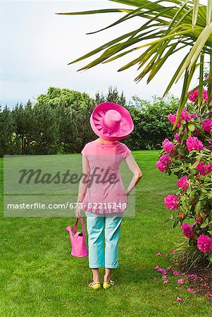 Femme en due forme chapeau rose festive dans le jardin