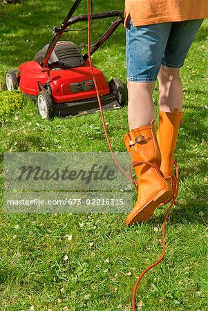 Woman mowing lawn with electric mower