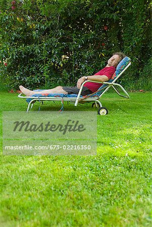 Man relaxing in lounge chair in backyard