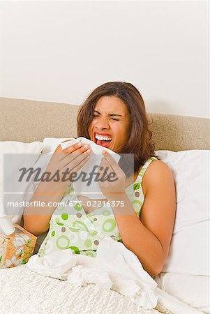 Woman sneezing in bed