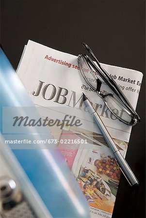Briefcase, eyeglasses and employment section of newspaper