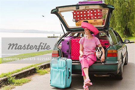 Femme et Boston Terrier chien posant avec voiture truffé de valises colorées