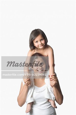 Porträt einer jungen Frau mit ihrer Tochter auf ihren Schultern und Lächeln
