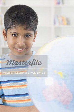 Portrait of a boy smiling behind a globe